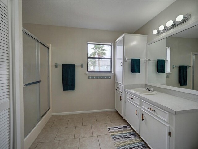bathroom with a shower stall, vanity, tile patterned flooring, and baseboards