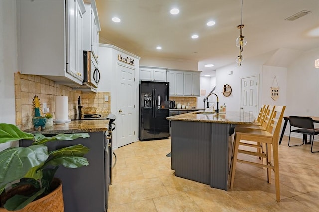 14878 Granada Dr Unit 403, Corpus Christi, TX 78418 - kitchen featuring stainless steel microwave, black refrigerator with ice dispenser, visible vents, dark stone counters, and a sink