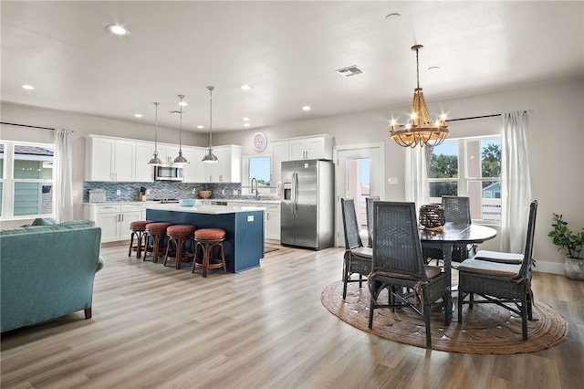 dining area featuring sink, light hardwood / wood-style floors, and a notable chandelier