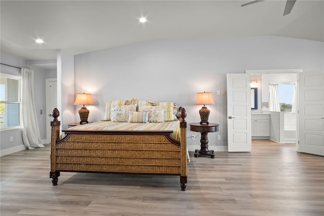 bedroom with multiple windows, ensuite bath, vaulted ceiling, and light wood-type flooring