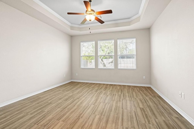 unfurnished room with a raised ceiling, ceiling fan, and crown molding