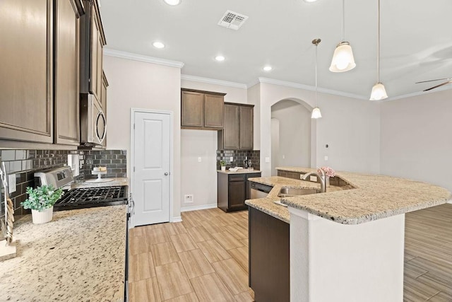 kitchen featuring sink, backsplash, hanging light fixtures, light stone countertops, and appliances with stainless steel finishes