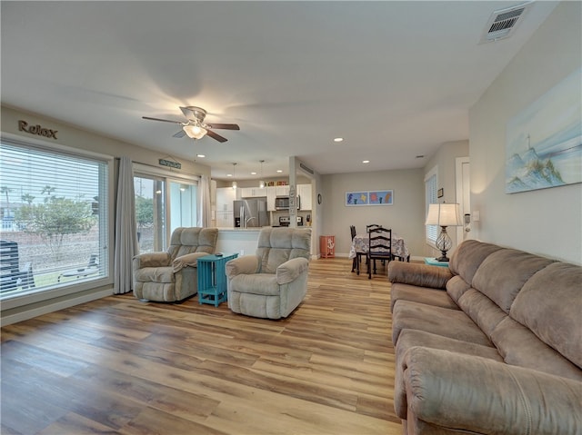 living room with light hardwood / wood-style floors and ceiling fan