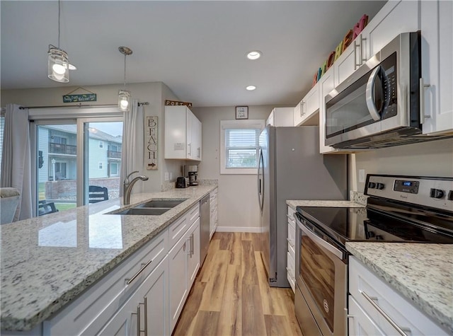 230 Cut Off Rd Unit 129, Port Aransas, TX 78373 - kitchen featuring appliances with stainless steel finishes, a sink, white cabinets, light wood finished floors, and baseboards