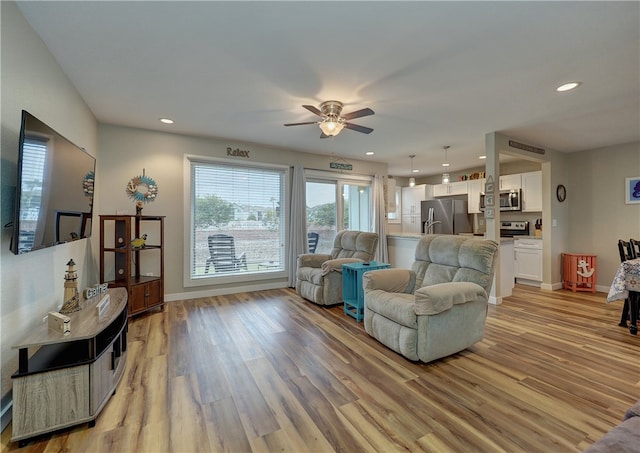 living room with ceiling fan and light wood-type flooring