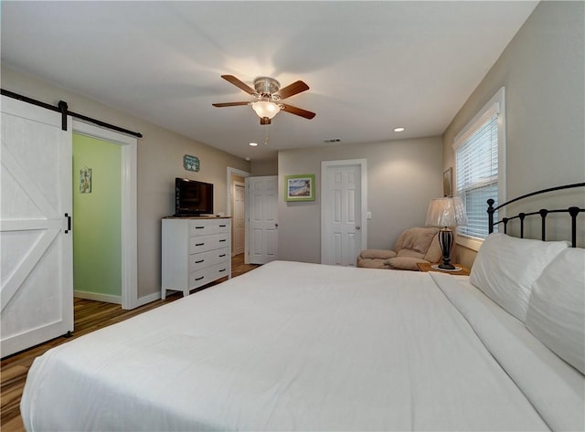 230 Cut Off Rd Unit 129, Port Aransas, TX 78373 - bedroom with a barn door, wood finished floors, a ceiling fan, recessed lighting, and baseboards