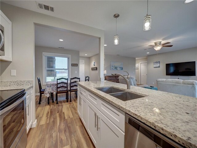 230 Cut Off Rd Unit 129, Port Aransas, TX 78373 - kitchen with a sink, appliances with stainless steel finishes, white cabinets, light stone countertops, and light wood finished floors