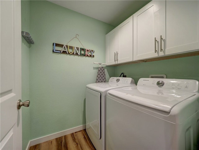 laundry room with washing machine and dryer, cabinets, and light hardwood / wood-style flooring