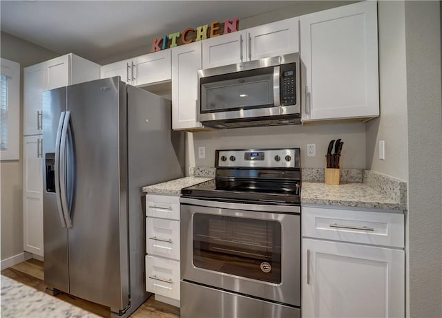 230 Cut Off Rd Unit 129, Port Aransas, TX 78373 - kitchen with stainless steel appliances, white cabinets, light wood-style floors, and light stone counters