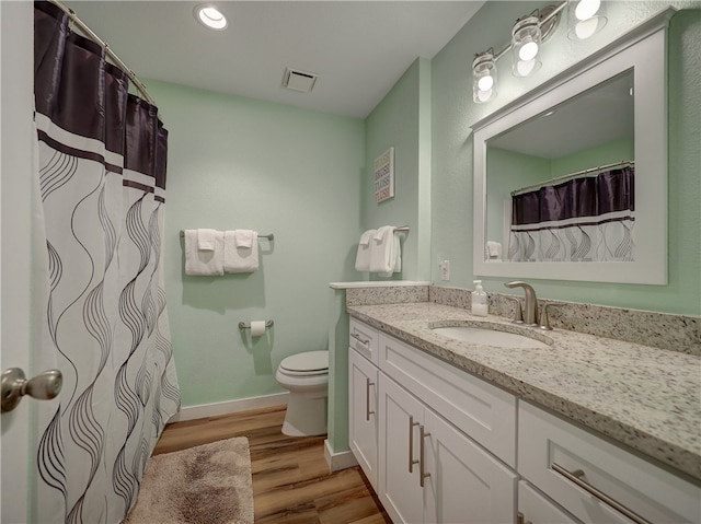 bathroom with toilet, vanity, and hardwood / wood-style floors