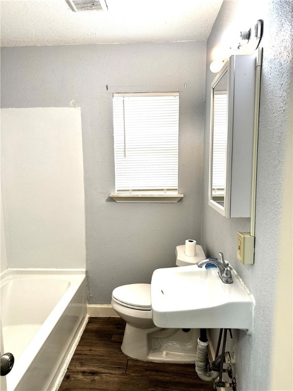 bathroom featuring a bathing tub, hardwood / wood-style floors, and toilet