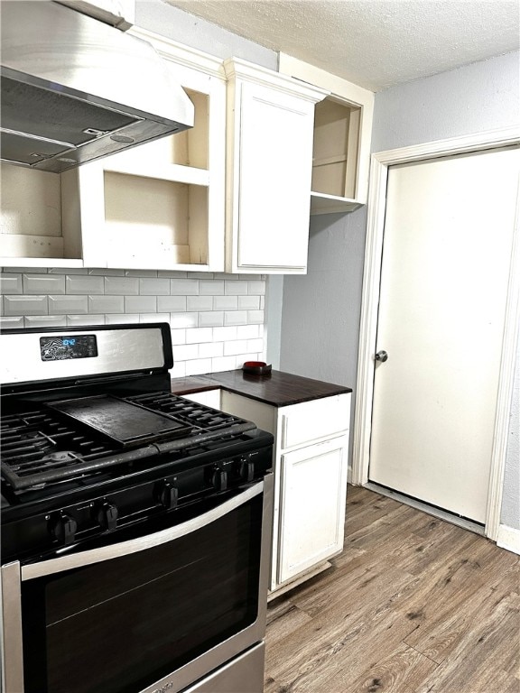 kitchen with backsplash, white cabinets, extractor fan, and stainless steel gas range