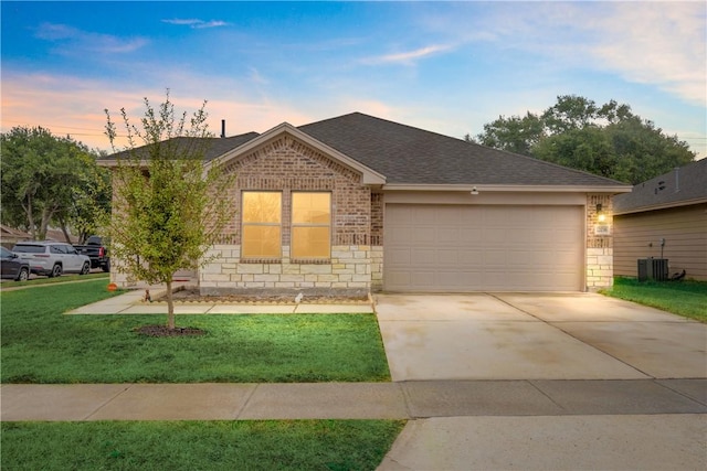 view of front of property featuring central AC, a garage, and a lawn