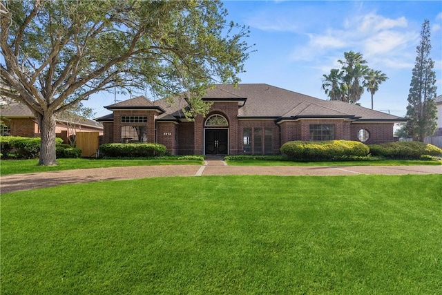 5913 Woodmere Dr, Corpus Christi, TX 78414 - view of front of home with a front lawn, brick siding, and roof with shingles