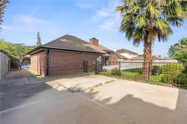 5913 Woodmere Dr, Corpus Christi, TX 78414 - view of side of home with brick siding, roof with shingles, a chimney, and a gate
