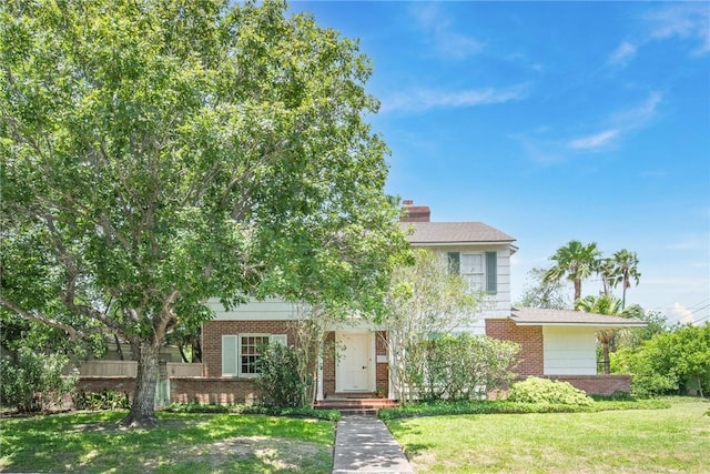 144 Cordula St, Corpus Christi, TX 78411 - view of property hidden behind natural elements with brick siding, a front lawn, and a chimney