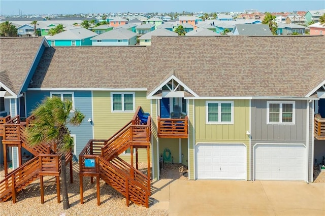 coastal inspired home with board and batten siding, driveway, a residential view, a garage, and a shingled roof