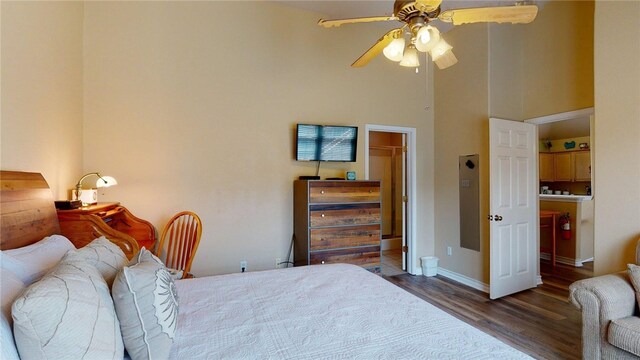 bedroom featuring a ceiling fan, baseboards, wood finished floors, and a high ceiling