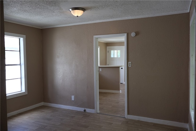 empty room featuring a wealth of natural light, hardwood / wood-style flooring, and ornamental molding