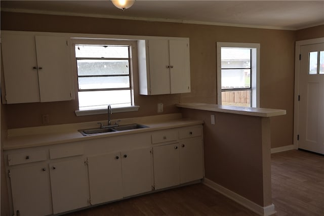 kitchen featuring white cabinetry, sink, kitchen peninsula, ornamental molding, and dark hardwood / wood-style flooring