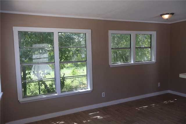 unfurnished room featuring dark hardwood / wood-style flooring, ornamental molding, and plenty of natural light