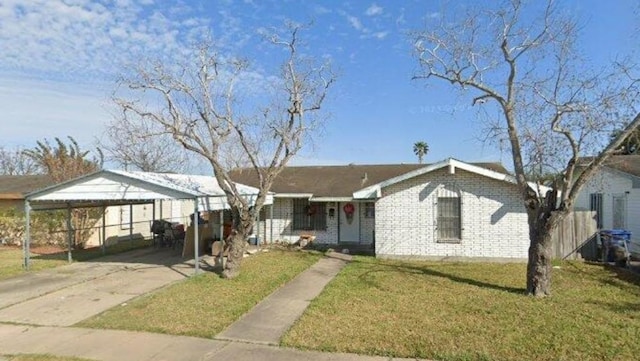 view of front facade featuring brick siding, a detached carport, concrete driveway, a front yard, and fence