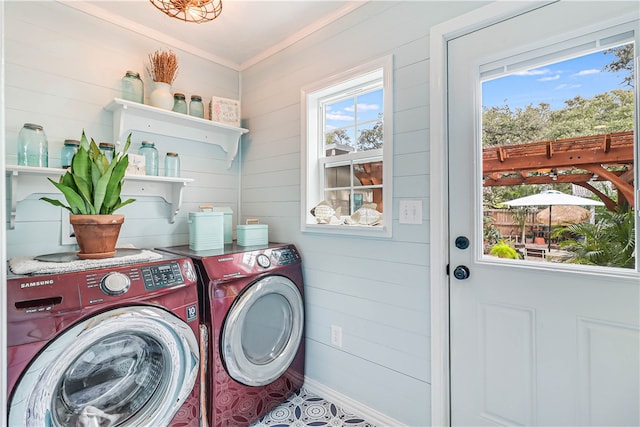 laundry room with plenty of natural light, wood walls, crown molding, and washing machine and clothes dryer