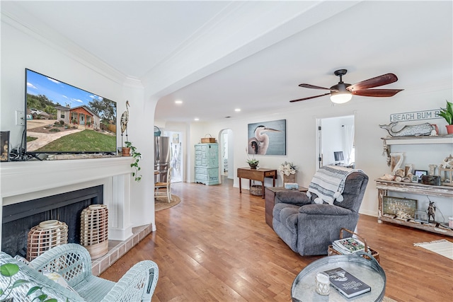 living room featuring a wealth of natural light, hardwood / wood-style flooring, ceiling fan, and crown molding