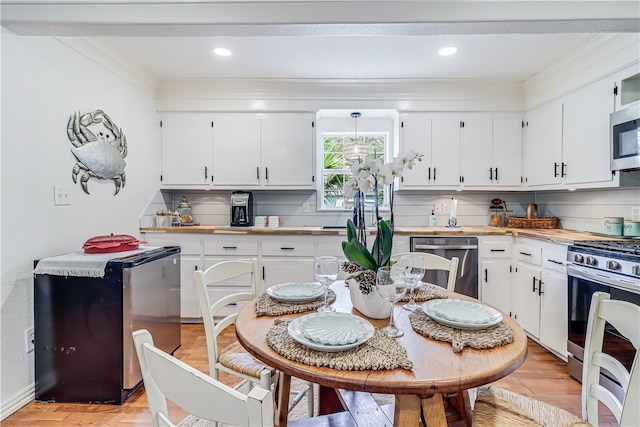 kitchen with stainless steel appliances, white cabinetry, light hardwood / wood-style flooring, and decorative backsplash