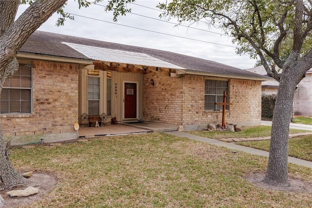 single story home with brick siding and a front yard