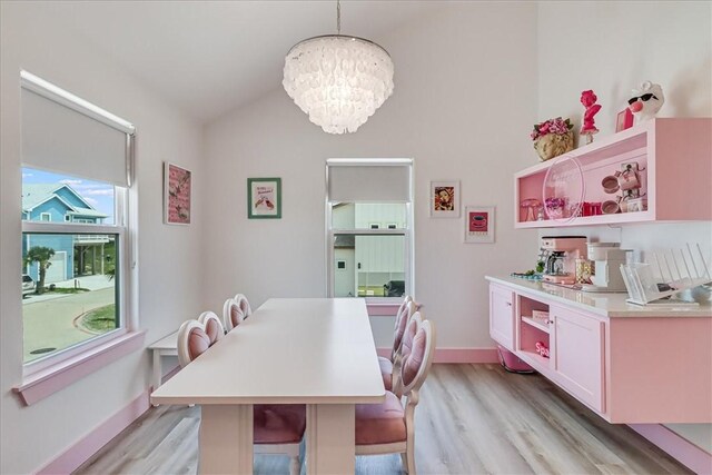 dining room featuring an inviting chandelier, baseboards, vaulted ceiling, and light wood finished floors