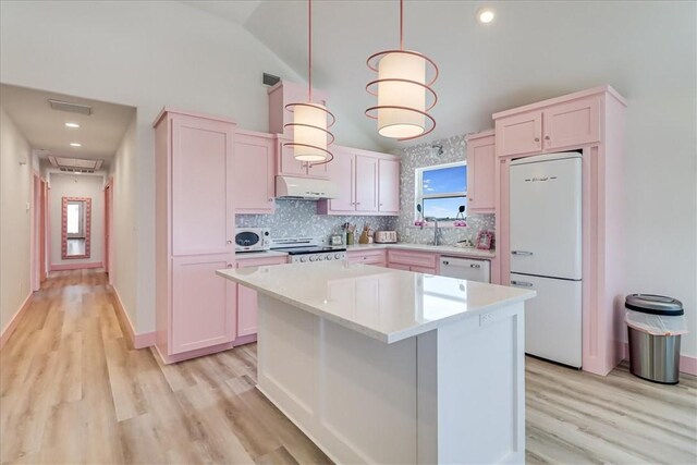 kitchen with white appliances, light countertops, under cabinet range hood, tasteful backsplash, and light wood finished floors
