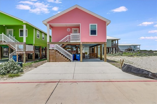 view of front of house with driveway, covered porch, stairway, and a carport