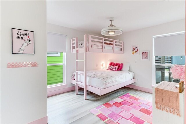 bedroom with baseboards, wood finished floors, and multiple windows