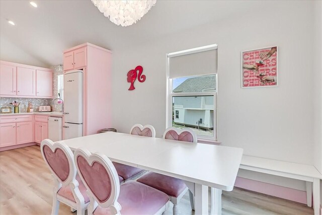 dining area with recessed lighting, lofted ceiling, an inviting chandelier, and light wood finished floors