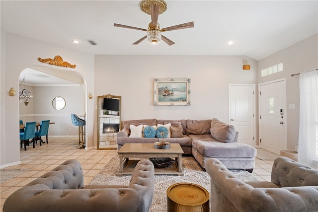 living room with arched walkways, lofted ceiling, light tile patterned flooring, recessed lighting, and a fireplace