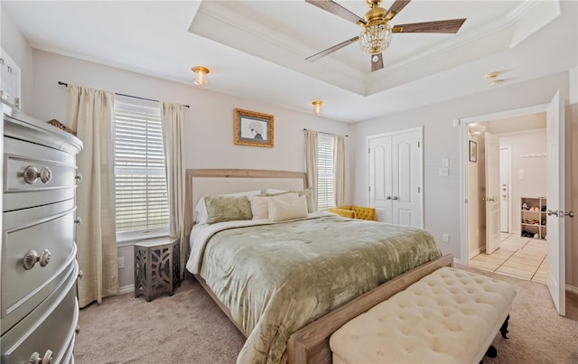 bedroom with a raised ceiling, light colored carpet, and multiple windows