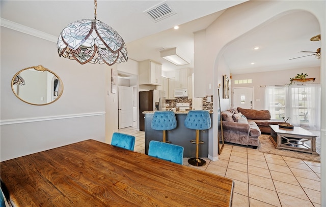 dining area with light tile patterned floors, visible vents, arched walkways, a ceiling fan, and recessed lighting