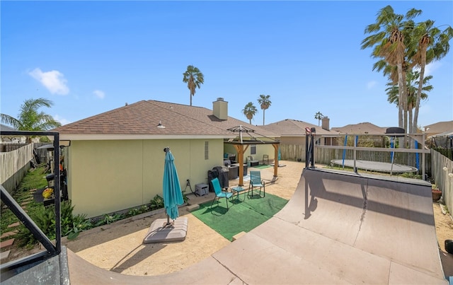 rear view of property featuring a shingled roof, a patio area, a fenced backyard, and stucco siding