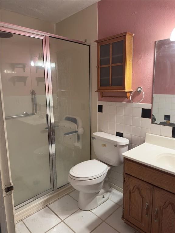 1203 N Hackberry St, Bishop, TX 78343 - bathroom featuring a stall shower, toilet, vanity, tile patterned flooring, and tile walls