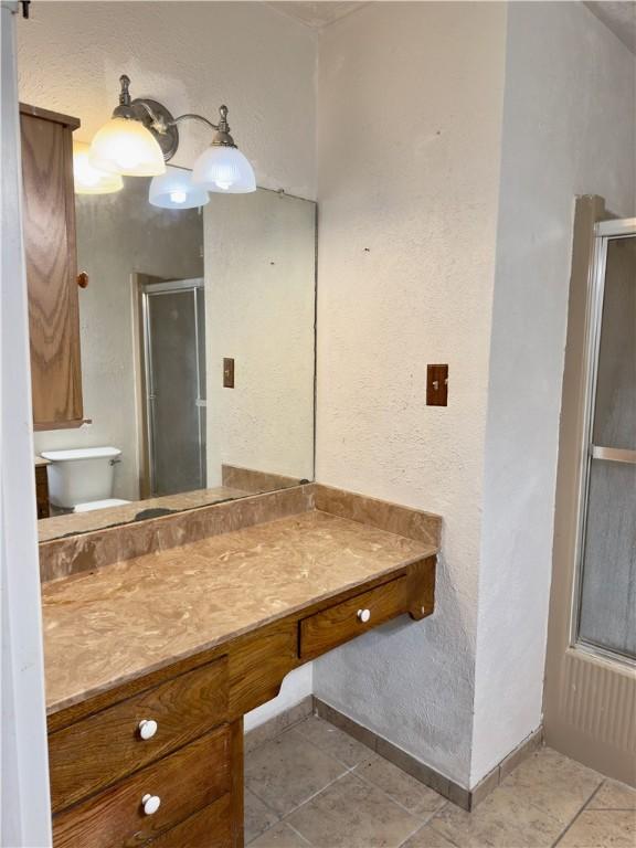1203 N Hackberry St, Bishop, TX 78343 - full bathroom with a stall shower, tile patterned floors, toilet, vanity, and baseboards