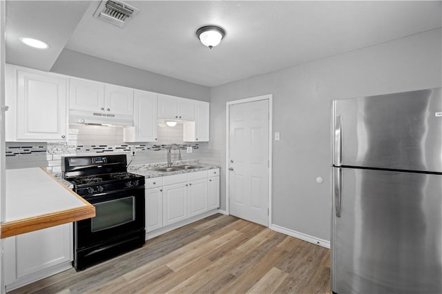 kitchen featuring sink, stainless steel fridge, black gas range, and white cabinets