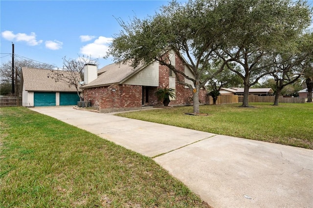 view of front facade with brick siding, fence, concrete driveway, a chimney, and a front yard