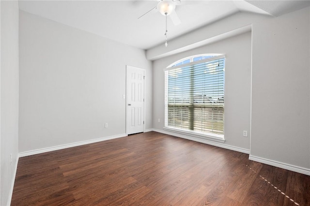 spare room with dark wood-style flooring, a ceiling fan, and baseboards