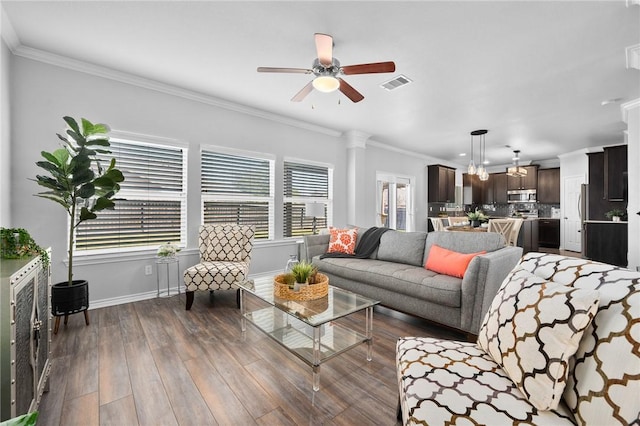 living area with baseboards, visible vents, dark wood-type flooring, and ornamental molding