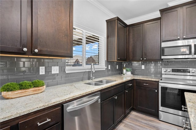 kitchen featuring stainless steel appliances, a sink, backsplash, and ornamental molding