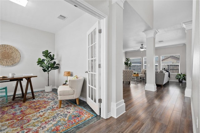 sitting room with decorative columns, visible vents, a ceiling fan, wood finished floors, and baseboards