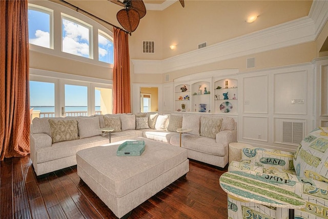 living room with visible vents, a decorative wall, dark wood-style flooring, and ornamental molding