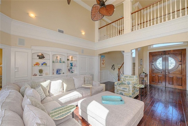 living area featuring ornate columns, dark wood-type flooring, visible vents, and a decorative wall