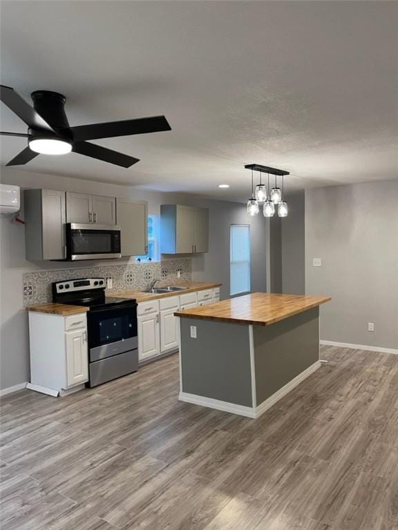 4414 Valdez Dr, Corpus Christi, TX 78416 - kitchen with stainless steel appliances, a wall mounted air conditioner, dark wood-type flooring, a kitchen island, and baseboards